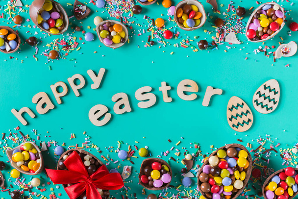Easter frame with chocolate eggs and sweets on a pink background. Happy easter text. Top view, flat lay - Photo, Image