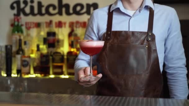 The camera approaches the bartender with an alcoholic cocktail in his hands, close-up - Footage, Video