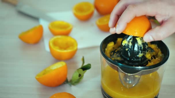 człowiek ręce sok świeżych owoców pomarańczy na sokowirówce 4k slow-motion zbliżenie wideo. Przygotowuję sok cytrusowy w domowej kuchni. Naciskam na wyciskacz. Elektryczne urządzenie wyciągowe stosowane do oddzielania uzdrowienia - Materiał filmowy, wideo