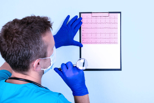Doctor looks at the cardiogram of the heart to establish a diagnosis. Medical concept. - Foto, afbeelding
