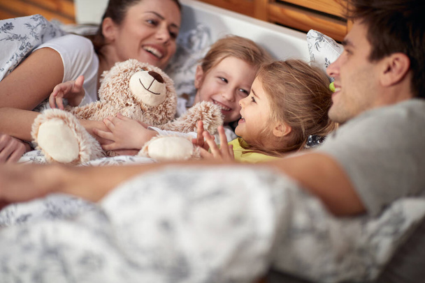 Young happy family enjoying beautiful morning in the bed at home together. Family, home, together - Foto, Imagem