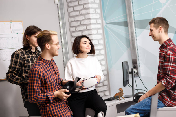 equipo de cuatro ingenieros creativos que trabajan con realidad virtual, mujer joven probando gafas VR o gafas sentadas en la sala de oficina - Foto, Imagen