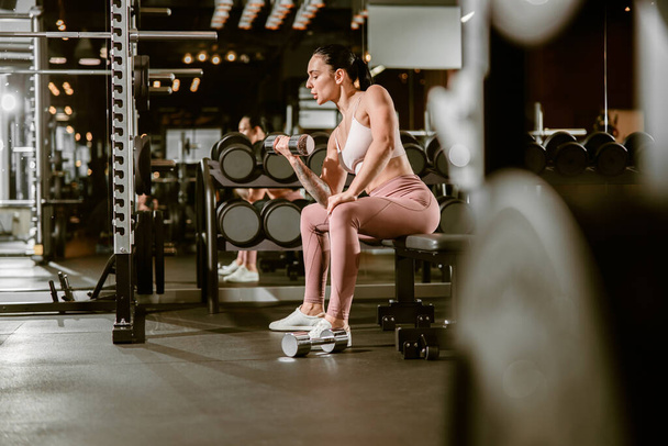 Νεαρή όμορφη καυκάσια ταιριάζει ισχυρή γυναίκα κάνει ασκήσεις στο γυμναστήριο - Φωτογραφία, εικόνα