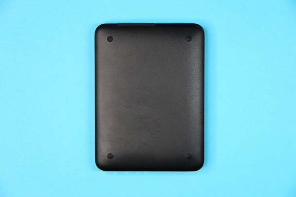 Disco duro externo negro sobre un fondo azul, vista posterior con un espacio de copia - Foto, Imagen