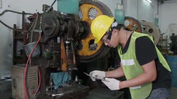 Egy ázsiai férfi mérnök vagy munkás használat előtt megvizsgálja és megjavítja a gépeket. ipari és mérnöki koncepció.  - Felvétel, videó