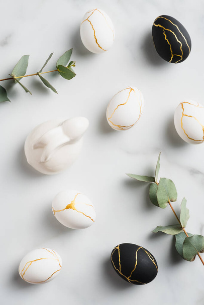 Easter flat lay composition with luxury easter eggs, bunny rabbit, eucalyptus leaves on marble background. - Foto, Imagem