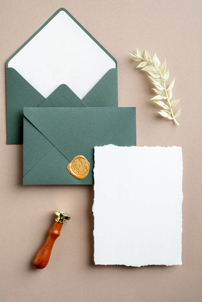 Wedding stationery set top view. Flat lay blank invitation card mockup, green envelopes, wax seal stamp, dried flowers. - Fotoğraf, Görsel