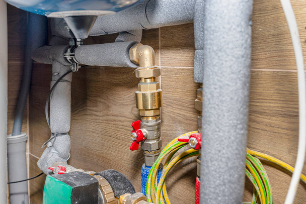 Vannes et tuyaux de gaz naturel dans une chaufferie moderne avec carreaux de céramique, pompe de circulation d'eau visible. - Photo, image
