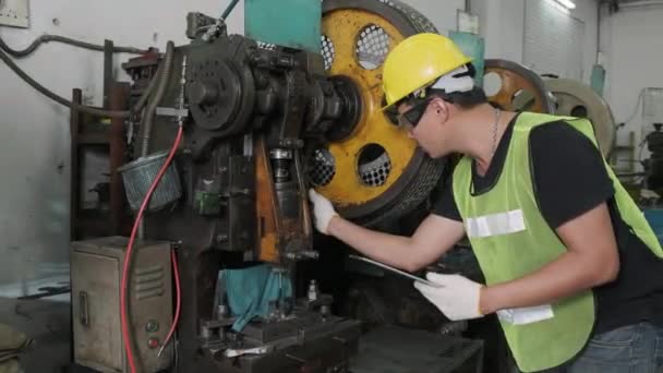 Een Aziatische mannelijke ingenieur of werknemer inspecteert en repareert machines voor gebruik. industrieel en technisch concept.  - Video