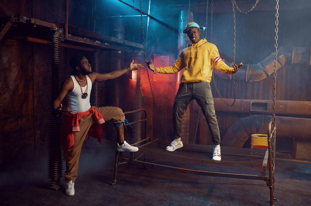 Dos raperos posando, actuando en estudio fresco, decoración underground. Artistas de hip-hop, cantantes de rap de moda, bailarines de break-dance - Foto, imagen
