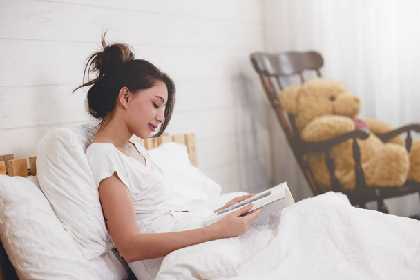 Woman lying in bed while reading a boo - Фото, изображение