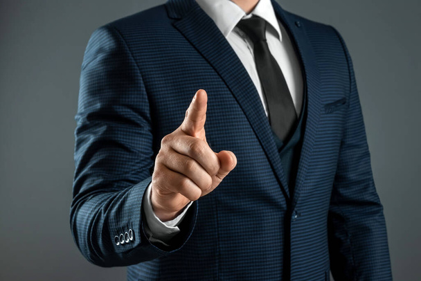 Male hand in suit shows index finger gesture on gray background. Navigator concept, head, close-up - Foto, Imagen