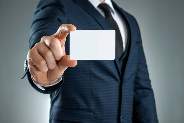 A man in a suit hands close-up shows a business card. mockup, layout. Concept for networking, business dating, important connections. Shot on a gray background - Foto, Bild