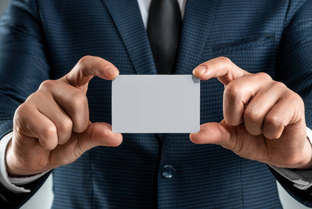 A man in a suit hands close-up shows a business card. mockup, layout. Concept for networking, business dating, important connections. Shot on a gray background - Zdjęcie, obraz
