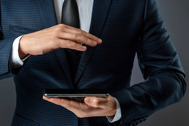A businessman in a business suit holds a smartphone in his hands. Online business concept, networking, freelance - Foto, Imagem