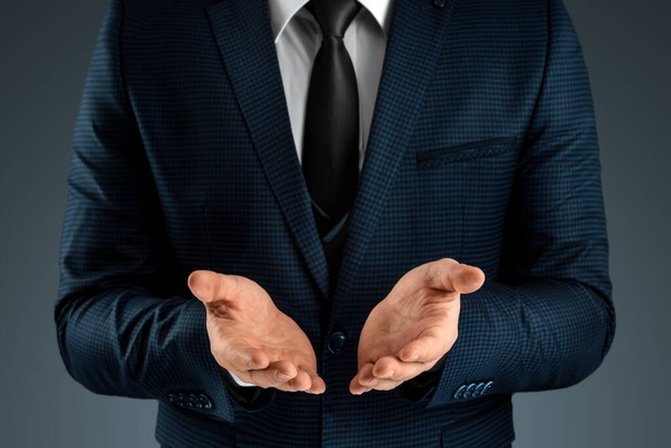 Male hand in a suit shows a palm up gesture on a gray background. Concept of request, bankruptcy, close-up - Foto, Imagem