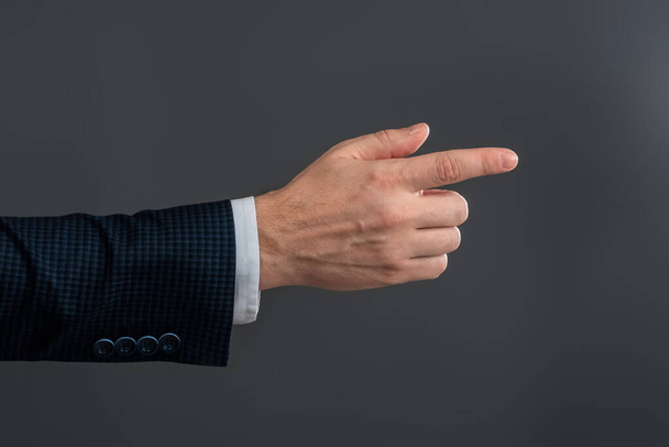 Male hand in suit shows index finger gesture on gray background. Navigator concept, head, close-up - Fotó, kép