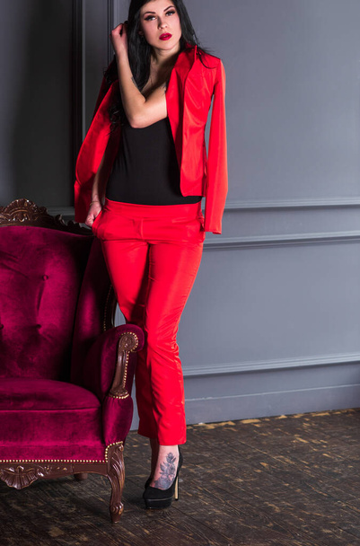 Брюнетка в красном костюме. Модный чувственный современный вид, симпатичный деловой стиль - Фото, изображение
