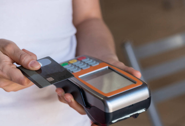 Tenir une machine à glisser de paiement par carte de crédit dans un restaurant  - Photo, image