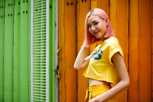 Street Fashion Woman with dying Pink Hair color wear yellow chic dress. Young Girl poses on Strong colorful wall art as summer trend style. copy space - Fotografie, Obrázek