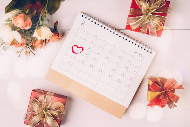 Calendar and flower with memo 14 February Valentine day on desk with blur bokeh background, reminder for surprise of love, romance and sweet, celebration and decoration, top view, holiday concept. - Fotó, kép
