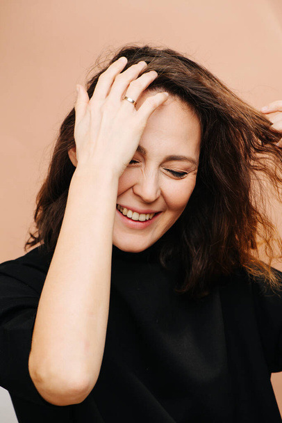 Painfully smiling middle aged woman trying to untangle hair strand - Foto, immagini