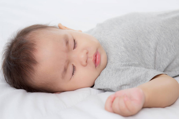 Portrait of asian little baby girl sleeping on bed in the bedroom at home, newborn napping with cozy and relax, infant innocence in bedtime, happy toddler cute, growth of child and emotion, indoors. - Foto, Imagem