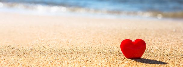 Concepto de San Valentín. Romántico símbolo de amor de corazón rojo en la playa de arena con espacio para copiar. Plantilla para composiciones inspiradoras y postales de citas. - Foto, imagen