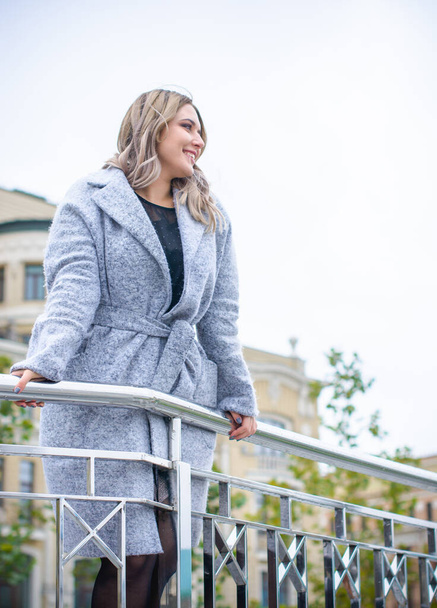 A woman of plus size, American or European appearance walks in the city enjoying life. A young lady with excess weight, stylishly dressed in coat at the center of the city. Natural beauty - Фото, зображення