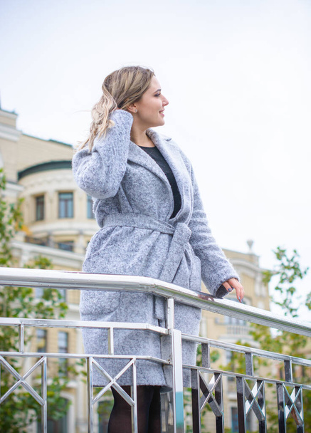 A woman of plus size, American or European appearance walks in the city enjoying life. A young lady with excess weight, stylishly dressed in coat at the center of the city. Natural beauty - Foto, immagini