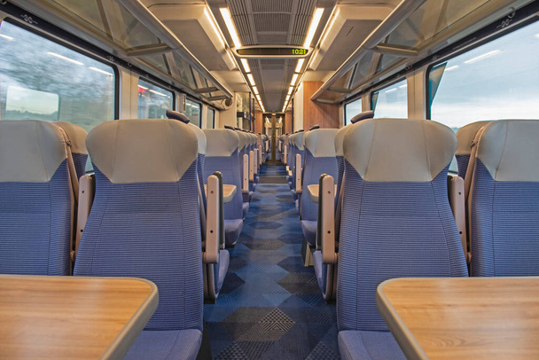 Vista interior en un vagón vacío y desierto con filas de asientos y mesas - Foto, Imagen