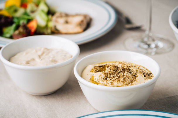 Hummus y baba ghanoush en la mesa de la cocina. De cerca. - Foto, imagen