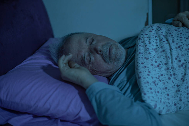 Senior man in slaap vallen in het bed tijdens middernacht - Foto, afbeelding
