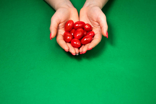 Elinde vişneli domatesler olan bir kız, yeşil bir arka planda, bir domates slaytı, domates - Fotoğraf, Görsel