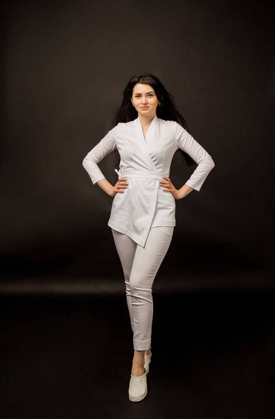 full-length woman doctor in a white uniform on a black background with a copy of the space - Фото, изображение