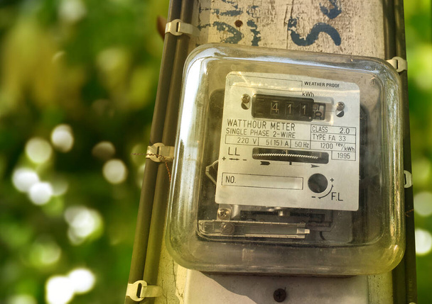 A small household electricity meter is hung on a light pole to record the monthly house consumption of electricity. Soft and selective focus. - Photo, Image