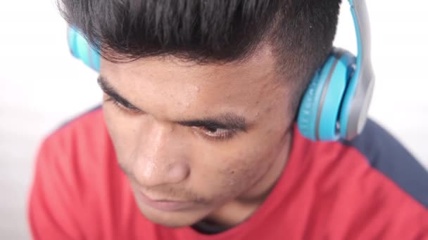 νεαρός άνδρας βάζοντας μπλε ακουστικά κοντά  - Πλάνα, βίντεο
