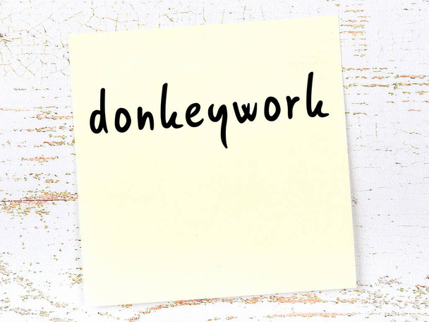 Note collante jaune sur mur en bois avec inscription manuscrite Donkeywork - Photo, image