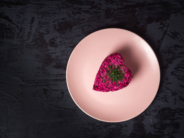 Valentines day festive dinner. Beetroot salad with kropom on a pink plate - Photo, Image