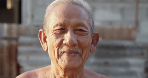 Slow motion scene van witharige Aziatische oudere mannen dragen geen kleren als gevolg van warm weer, slechte status, ouder dan zeventig lacht gelukkig op de zonsondergang licht in de avond. - Video