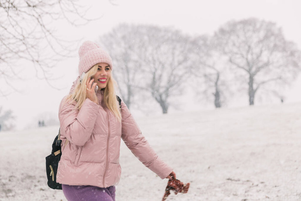 woman in a powder jacket speaks on the phone, winter background - Foto, Bild