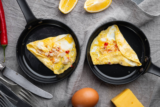 Gebakken ontbijt omelet met een krab vlees en kaas, op braadijzeren pan, op grijze achtergrond, bovenaanzicht plat gelegd - Foto, afbeelding
