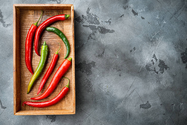 Red and green chili pepper set, in wooden box, on gray background, top view flat lay , with copyspace  and space for text - Photo, Image