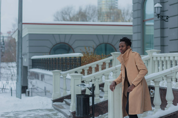jovem afro-americano no inverno contra o pano de fundo de um edifício majestoso. Foto de alta qualidade - Foto, Imagem