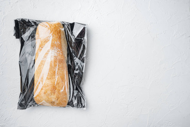 Hoja de pan de ciabatta de grano entero artesanal recién horneado en una bolsa de mercado, sobre fondo blanco, vista superior plana, con copyspace y espacio para el texto - Foto, Imagen