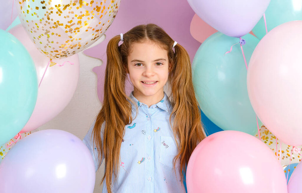 1 white girl 10 years old with pink, yellow, blue balloons smiles - Foto, Imagem