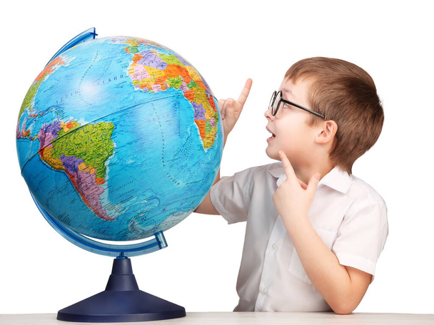 un ragazzo con gli occhiali, uno studente delle elementari, accanto a un globo, isolato su uno sfondo bianco - Foto, immagini