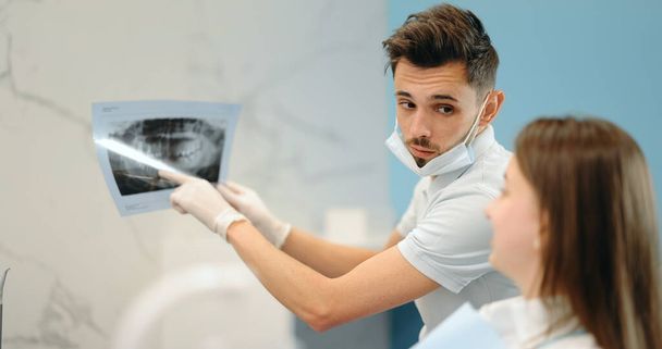 Οδοντίατρος που δείχνει ακτινογραφία γνάθου για νεαρό ασθενή - Φωτογραφία, εικόνα