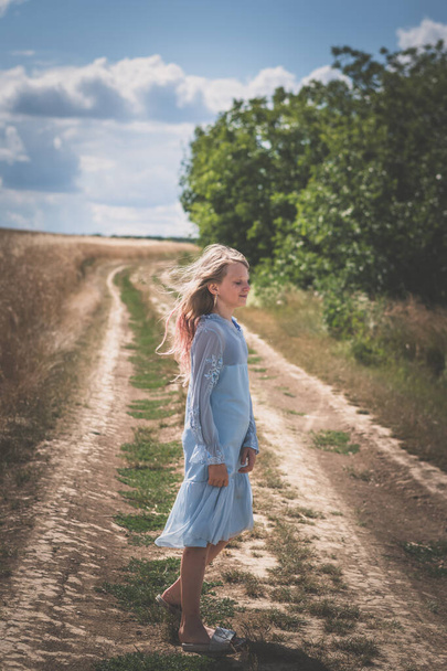 menina com longos cabelos loiros esperando no caminho rural no campo - Foto, Imagem