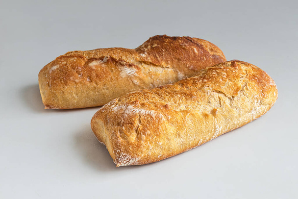 Fresh pastries - two French mini baguettes with a delicious crispy crust on a light background - Photo, Image